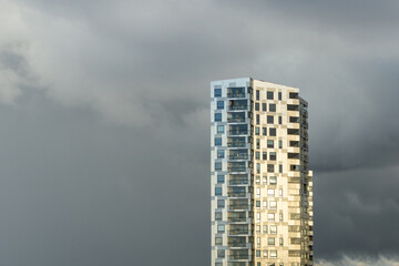Fototapeta premium Stavanger high-rise building reflecting sunlight under storm clouds