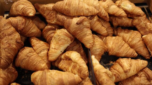 Fresh golden croissants fill supermarket bakery display with flaky layered pastry and buttery crust offering classic breakfast food and freshly baked treats for customers
