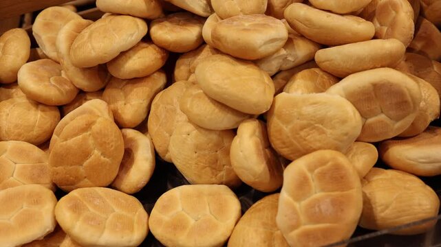 Fresh golden bread rolls arranged in supermarket bakery display with fresh crusts and classic shapes offering everyday baked goods for grocery shoppers and families daily