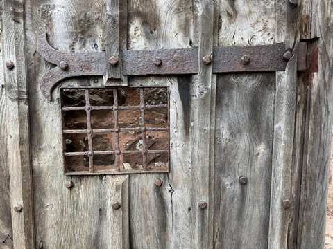 A beautiful ancient wooden door with an iron grid and hinge. England, UK.