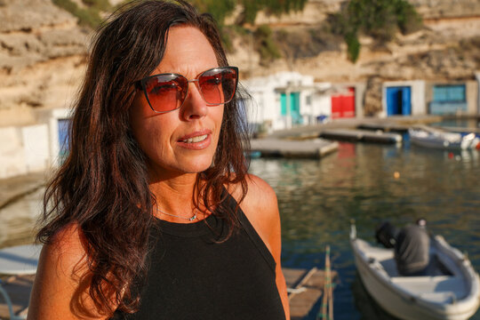 Beautiful woman visiting the fishing village Mandrakia with colorful doors on the Greek island Milos in Greece.