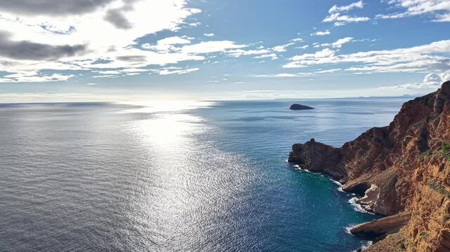 Reflective Sea Horizon Midday Glittering Surface, Drone Capturing Calm Cobalt Waters And Small Islet By Rugged