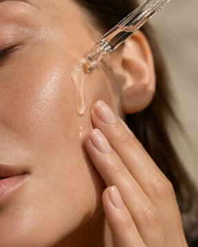 Skincare serum being applied to glowing facial skin in close up
