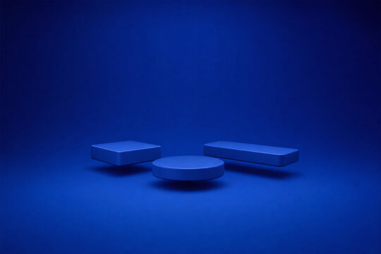 Three geometric platforms in different shapes and heights arranged in a minimalist blue studio setting.