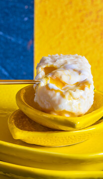 Creamy mango ice cream on yellow dinnerware against a blue and yellow color-blocked background.