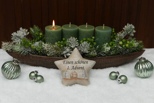 Stimmungsvolle Adventsgesteck zum 1. Advent, mit gr&uuml;nen Kerzen und dem Schriftzug einem sch&ouml;nen 1. Advent.