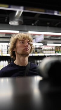 Vertical screen supermarket employee returns products to shelves organizing merchandise and restocking items while keeping the grocery aisles neat and ready for customers