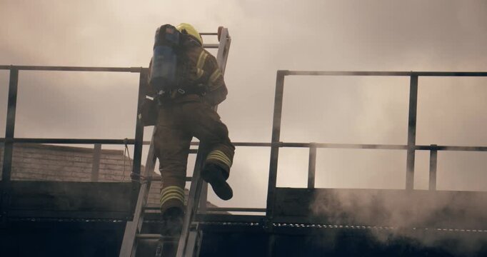 Firefighter crew &ndash; emergency service fireman rescue in action. In uniform and gas mask in response to fire with firefighting ladder against burning building releasing smoke.