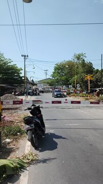 Motorcycle waiting at a closed railway crossing on a sunny day
