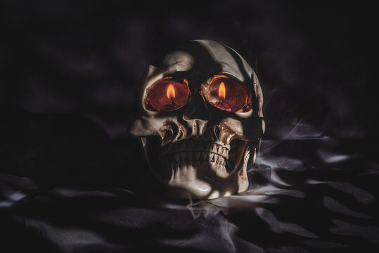 Human skull with eerie glowing eyes and mysterious smoke