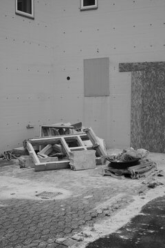 Monochrome view of construction debris and wood scraps beside a building wall