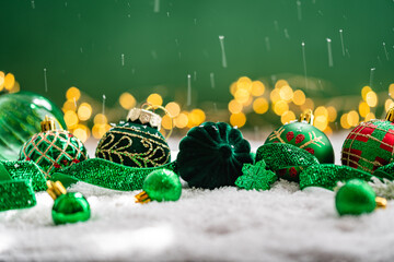 Naklejka premium A Christmas background featuring an abundant mix of green velvet and glass baubles, a snowflake, and plaid ornaments on snow, with falling snowflakes and warm twinkling lights behind.