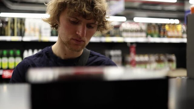 Shopper finds a good product and studies the package with interest before choosing it showing satisfaction with quality ingredients and a confident grocery purchase today