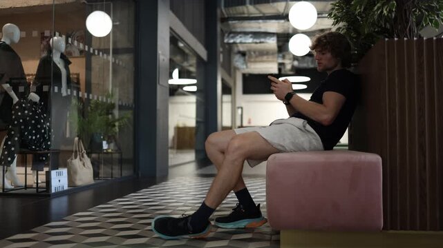 Passive student waits for a woman to approach him first while looking at his phone showing lack of initiative shyness and hesitation in dating and modern relationships today