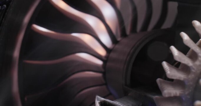 Slow motion close tracking shot of jet engine turbine blades rotating inside test bay maintenance interior, macro probe view.