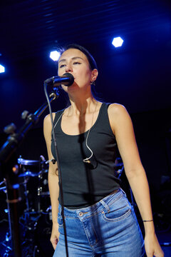 Young female singer performs vocal sound check on blue lit stage