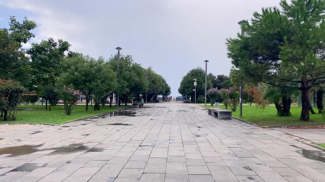 Park walkway leading seaward, eye-level view through Lech and Maria Kaczynski Park in Batumi, showing pedestrian access to the waterfront for urban planning, recreation, tourism and public space use