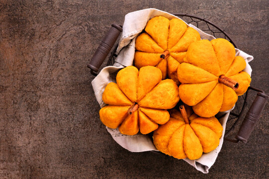Basket of autumn pumpkin shaped buns. Top view on a dark background.
