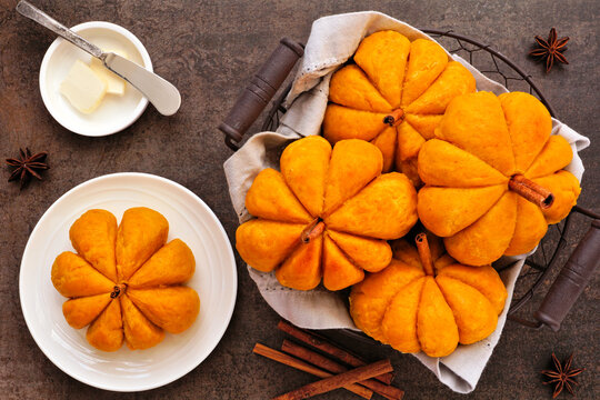 Fall pumpkin shaped buns. Above view table scene over a dark background.