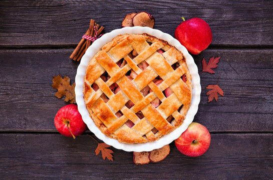 Homemade autumn apple pie with frame of ingredients. Above view table scene over a dark wood background.