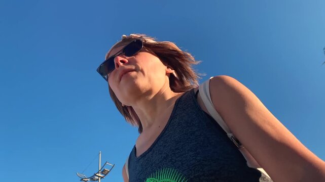 Woman rollerblading in low-angle view along a palm-lined promenade, showing outdoor fitness, active transport, coastal recreation, personal mobility for sports 