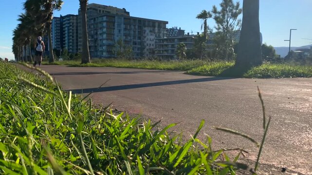 Inline skater rolling past camera, ground-level side view on a paved path, showing wheel motion and skating technique for sports training, recreational fitness, urban exercise, equipment performance