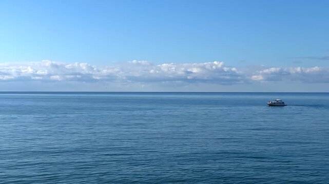 Motorboat cruising wide shot across open sea near the horizon, showing small vessel travel for coastal tourism, marine transport, recreational boating, excursion services and regional waterfront mobil