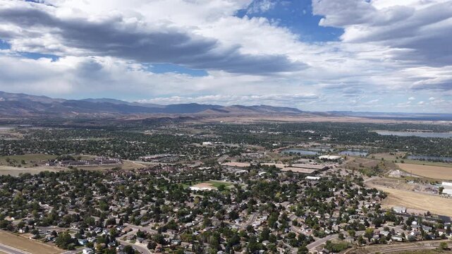Aerial of forested suburban neighborhood overlooking valley and Rocky Mountain range in Loveland Colorado in summer