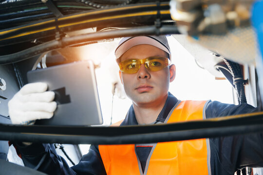 Mechanic checks inspecting pipes system of hydraulic hose valves of machinery with tablet in industrial setting