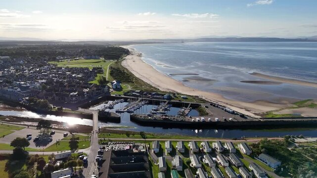 Elevated wide aerial drone shot of Nairn Harbour, sandy beach coastline, marina, and Moray Firth in Nairn, Highland, Scotland