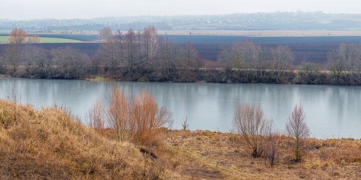 Autumn river valley with dry fields and bare trees along the bank