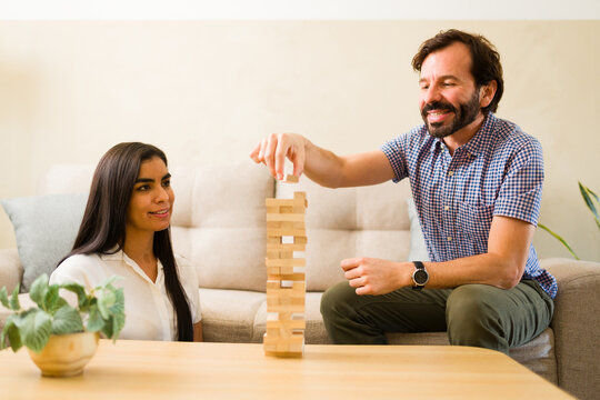 Cute couple enjoying board game at home, playing jenga building wooden blocks during fun leisure time together