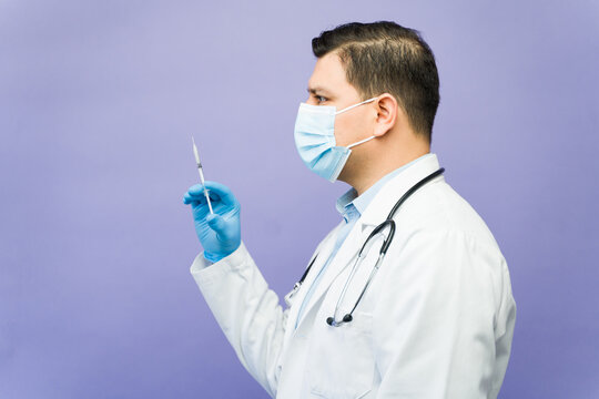Medical professional wearing mask and gloves holding syringe preparing injection for vaccine administration