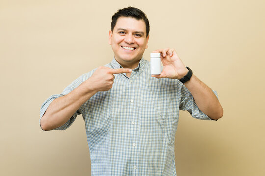 Happy man recommending supplement or medication bottle for health, wellness, and healthy living