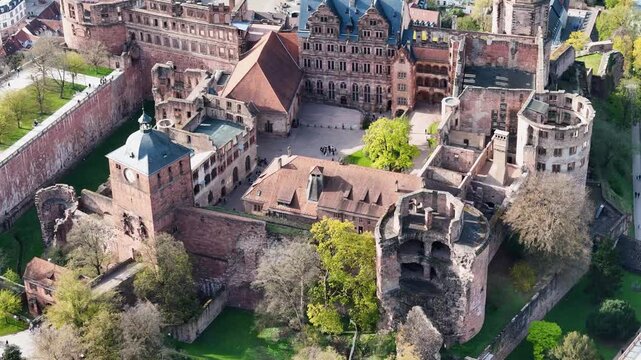 heidelberg castle clock tower green spire moat garden walls red sandstone ruins hilltop fortress baden wurttemberg germany aerial orbit drone footage elevated view historic heritage site landmark