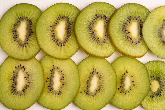 Fresh kiwifruit background closeup with whole kiwi fruit and juicy green slices row texture, healthy organic tropical dessert vitamin food macro pattern, white backdrop horizontal copy space.