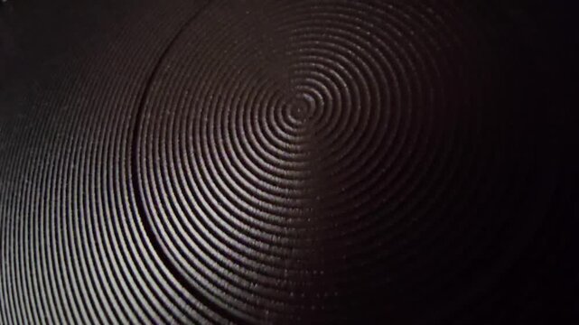 Close up of dark concentric circular pattern center with warm highlighted edge texture background.