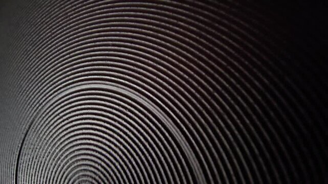 Abstract rotating concentric rings texture with subtle light transition dark background macro.