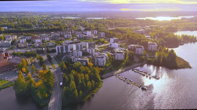 Aerial drone view of a city shore in Finland H&auml;meenlinna featuring modern architecture living suburb and lush green trees and traffic on streets. 