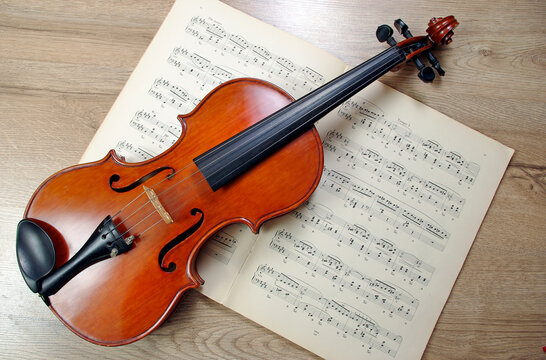Violin and musical notes on a wooden table. Top view