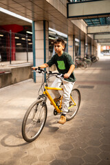 Fototapeta premium Boy riding yellow bicycle outdoors in urban environment