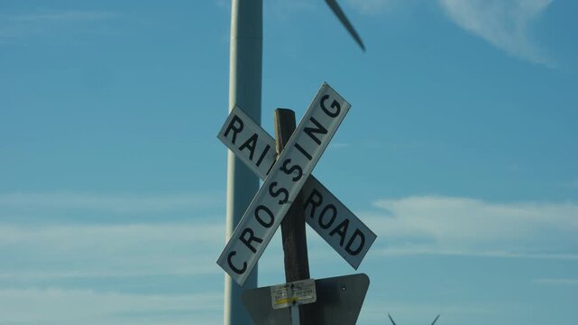 Railroad crossing sign in blue sky With A Windmill in the background