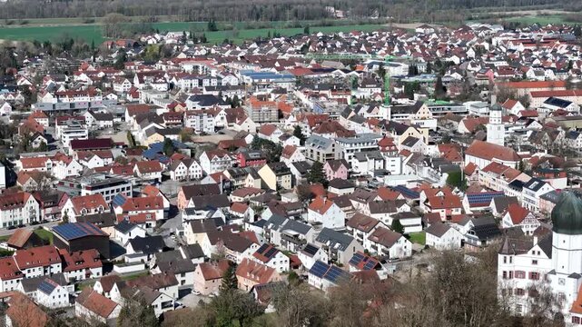 illertissen rooftops aerial orbit vohlin castle onion dome edge industrial storage silos dense residential streets farmland forest treeline construction crane bavarian rural germany drone footage