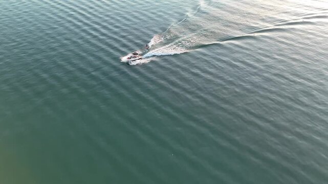 Aerial view of wakeboarder riding behind a motorboat on a lake