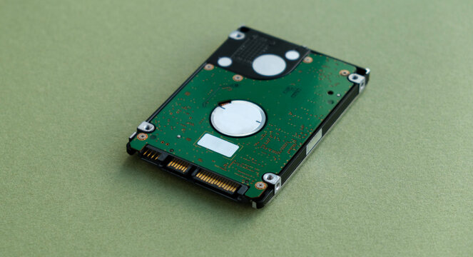 Technology and hardware photography featuring a computer hard disk drive (HDD) circuit board and SATA connectors isolated on a light green textured background