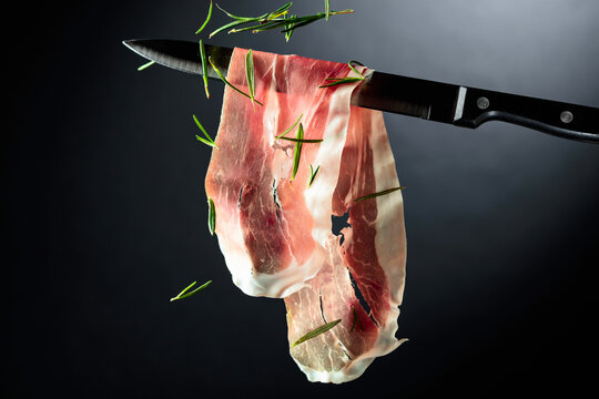 Sliced prosciutto on a kitchen knife.