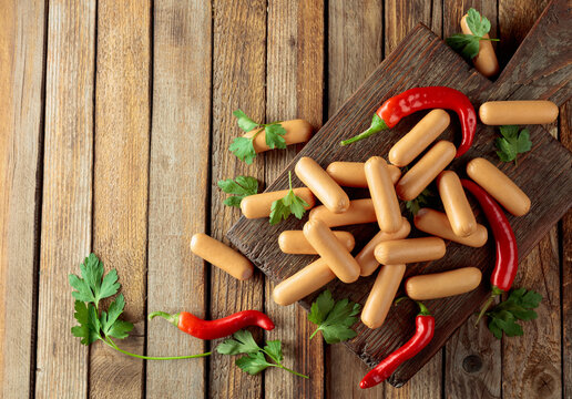 Sausages with red pepper and parsley on an old wooden table.