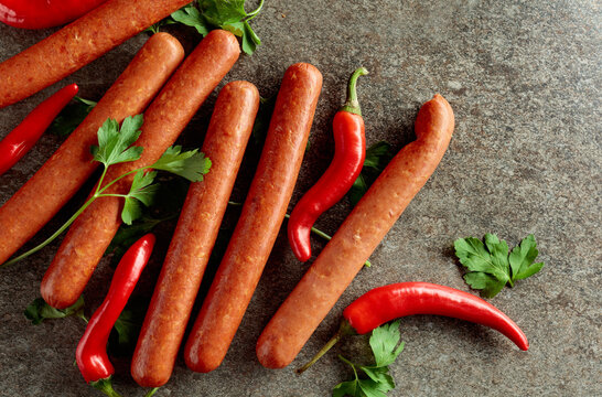 Sausages with red pepper and parsley on a stone table.