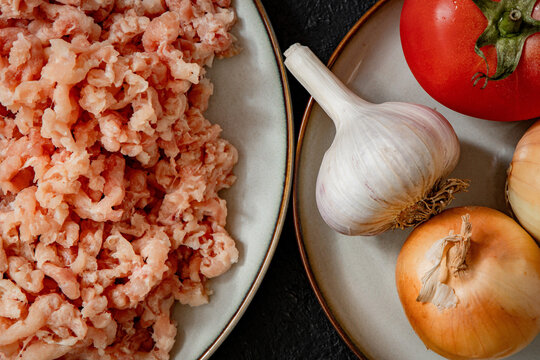 Raw minced meat on plate with garlic onion and tomato