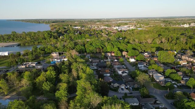 Moving backwards aerial view of St. Catharines, Ontario, Canada, revealing the popular recreational area, Sunset Beach on the Welland Canal in Lake Ontario. Shot late afternoon, May, 2023.